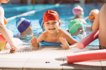 happy children kids group at swimming pool class learning to swim