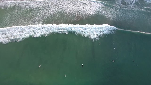 Aerial birds eye view of surfers and waves at Sandy Bay, New Zealand