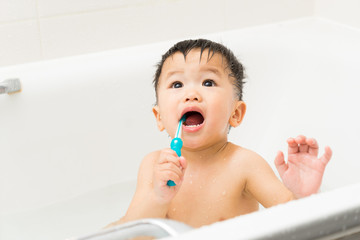 Asian baby uses toothbrush in the bathroom