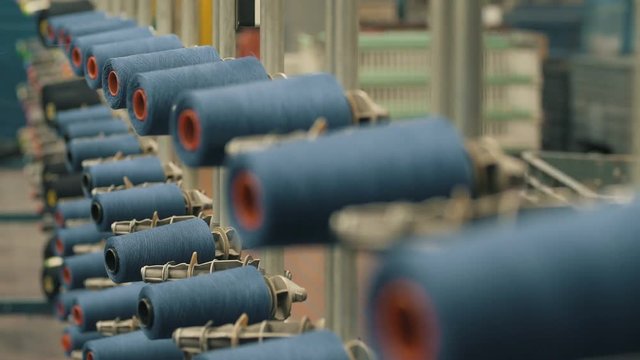 Row of colorful thread spools. Manufacture industrial textile. Manufacture industrial textile spinning. Textiles and Fabrics. Shot of colorful rolls of woolen. Needlework, sewing and tailoring concept