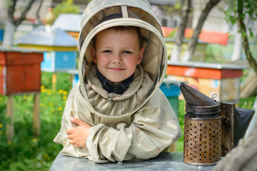 The boy in protective clothing beekeeper works on an apiary. Apiculture.