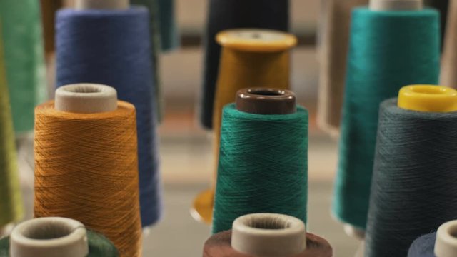 Textiles and fabrics. Row of colorful thread spools. Manufacture industrial textile. Manufacture industrial textile spinning. Textiles and Fabrics. Shot of colorful rolls of woolen. Needlework, sewing