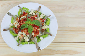Spicy shrimp salad with fish sauce in white dish.