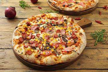 pizza con carne ,prosciutto, salsiccia,funghi,cipolla sfondo tavolo rustico