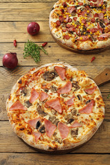 pizza con prosciutto e funghi sfondo tavolo rustico © denio109