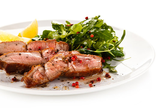 Grilled steak - fillet mignon on white plate with green salad