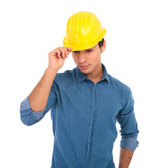 young construction engineer holding his safety helmet and looks down