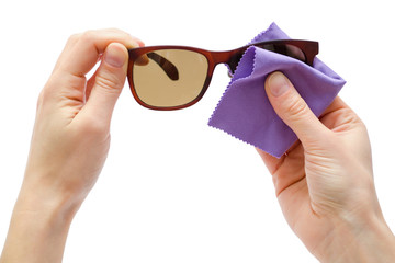 female hand rubbing sunglasses with cloth.