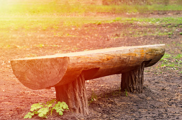 bench made of logs on lawn in forest