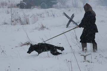 Person with dog walking through the snowy field.