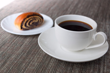 Loaf with poppy seeds and a Cup of coffee on the table. Selective focus.