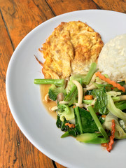 stir fried vegetables with Thai Omelette (scrambled eggs) with rice in white plate on rustic wooden background. Vegetarian Food, healthy food.