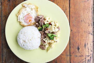 fried cauliflower, Broccoli, chicken and fried egg with rice in plate on wooden background .thai food