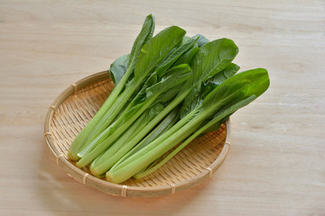 ザルに盛った小松菜　木目背景