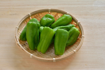 ザルに入ったピーマン　木目背景
