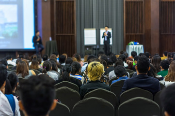 Speaker on the stage with Rear view of Audience in the conference hall or seminar meeting, business...