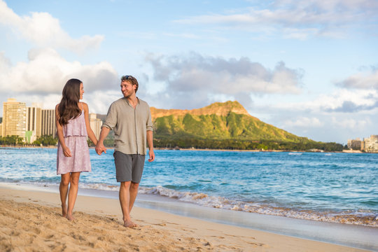 Couple walking on Waikiki beach Hawaii vacation. Happy couple in love relaxing at sunset on tourist famous travel destination in Honolulu, Oahu, Hawaii. - Powered by Adobe