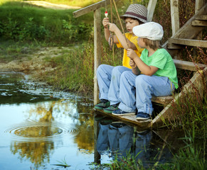 Happy boys go fishing on the river, Two children of the fisherman with a fishing rod on the shore of lake