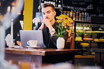 A man using laptop in a cafe.