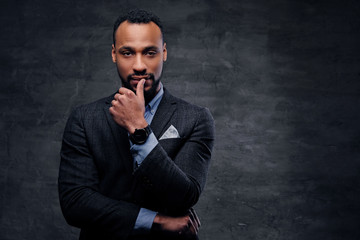A stylish black male dressed in a suit over grey background.