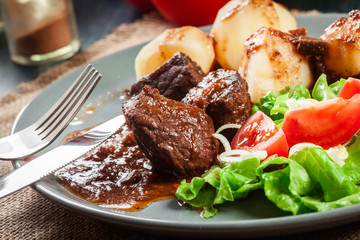 Pork meat stew served with potatoes and vegetable salad