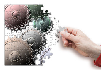 Female hand disassemble and assemble a gear - concept image in puzzle shape