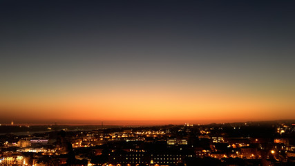 Fototapeta premium City night from the view point on top of hill at beautiful sunset. Bird view over the city at night with abstract urban night lights in Lisbon, Portugal