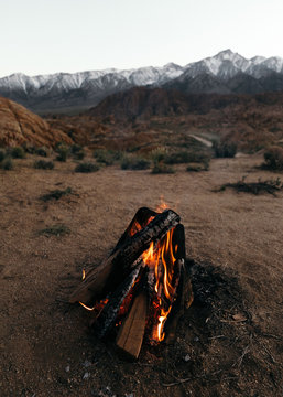 Campfire burning in desert against snowcapped mountain