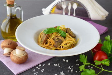 Pasta with mushrooms and pesto sauce in a white plate on abstract bckground. Italian lifestyle. Healthy eating concept