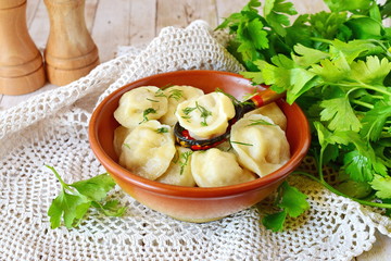 Traditional russian pelmeni with minced meat and onions filling in a brown ceramic bowl
