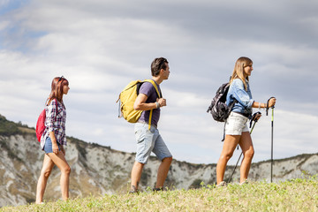 group of young hikers walking toward the horizon over the mountain