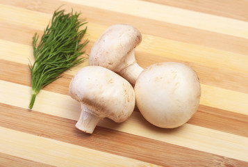 Fresh white mushrooms champignon on wooden background.