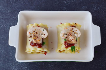 Vegetarian lasagna in rolls with mushrooms, paprika, olives, tomato sauce in a ceramic form ready for oven. Healthy food. Vegetarian food. Step by step cooking