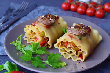 Ready to eat vegetarian lasagna in rolls with mushrooms, paprika, olives, tomato sauce on a brown ceramic plate. Healthy food. Vegetarian food. Step by step cooking