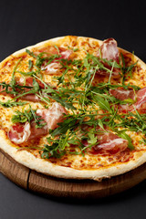 Hot pizza Prosciutto on a rustic wooden table.