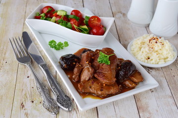 Veal meat cooked with smoked prunes on a white plate with fresh vegetable salad and boiled rice. Healthy eating concept