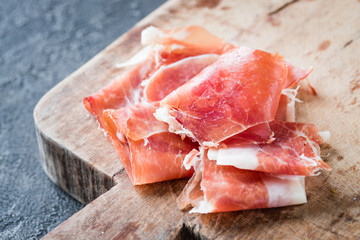 Closeup of Spanish ham jamon serrano or Italian prosciutto crudo on old wooden board