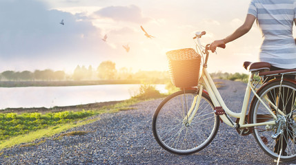 Fototapeta na wymiar woman standing with vintage bicycle, relaxing in summer sunset nature rural with flying birds