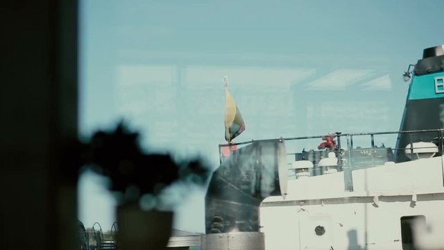 A view from a window looking down on a big ferry boat that has Lithuanian flag waving on its deck.