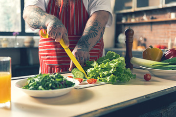 Fat man chopping vegetables by knife