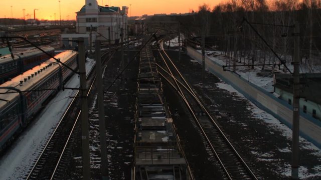 Above view of freight train with flatcars passing by railway station at sunset