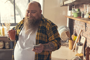 Man with a mug and his cellphone in both of his hands