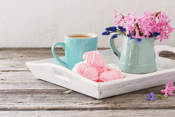 A cup of coffee and a bouquet of flowers on a wooden table
