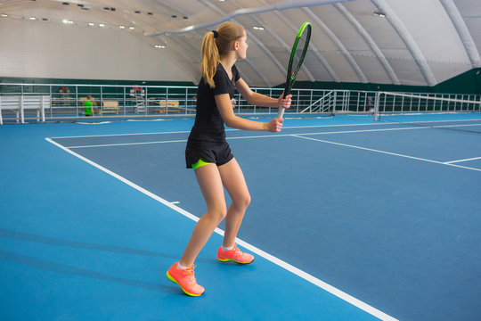 The young girl in a closed tennis court with ball