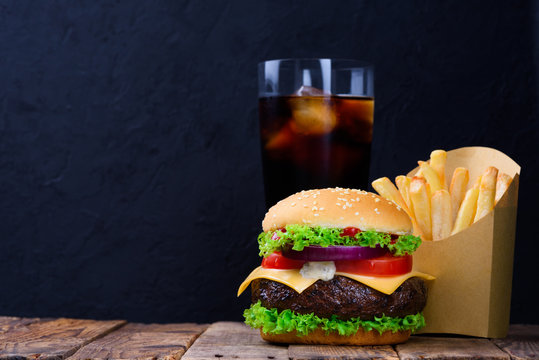 Burger menu with french fries and soft drink on wooden table