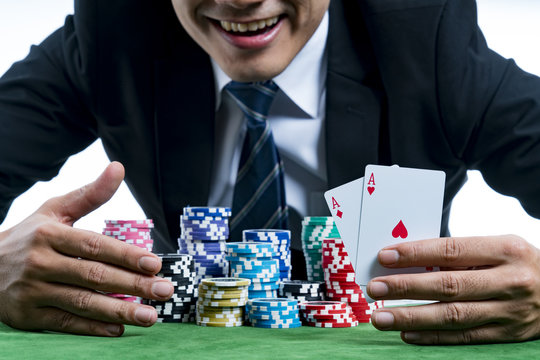The poker gambler is showing a pair of aces and smiling hold bet a large stack with arms