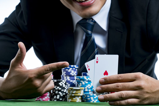 The poker gambler use finger pointing to a pair of aces and hold bets a large stack with arms