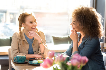 Happy female friends speaking in cafe