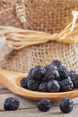 Dried aronia berries (chokeberries) in wooden spoon. Copy space