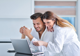 Portrait of a couple in the kitchen and using a laptop